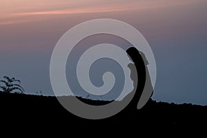 Silhouette of woman kneeling on mountain