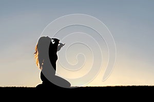 Silhouette of Woman Kneeling in Prayer and Surrender