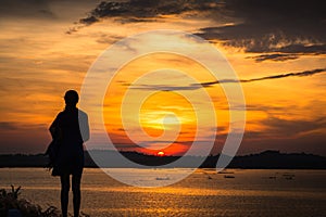 Silhouette of woman at lake ,sunrise background