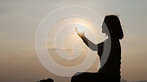 Silhouette of a woman making a wish while the sun was rising. Eucharist healing blesses the Lord, helps to repent