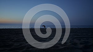 Silhouette woman making yoga on beach late evening. Girl stretching on seacoast.