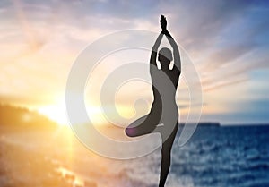 Silhouette of woman making yoga over sea sunset