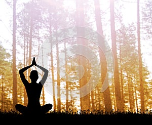 Silhouette of a woman meditating in the forest