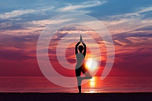 Silhouette of Woman Meditating in Yoga pose by the Sea at Sunset. Nature Meditation Concept. Low key photo. relax time