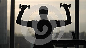 Silhouette of woman middle age doing exercise with dumbbells.