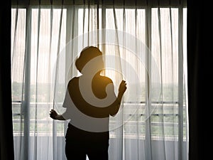 Silhouette woman opening curtain in the bedroom