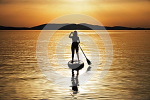 Silhouette of woman paddling at sunset on a stand up paddleboard SUP in Croatia, Adriatic Sea, near Sibenik. Tourism concept
