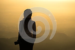 Silhouette of a woman photographer standing in dry grass field