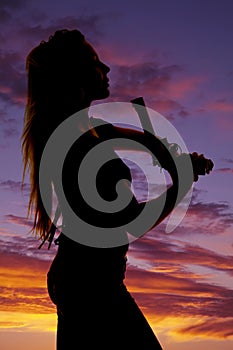 Silhouette of a woman with a pistol pointed up close