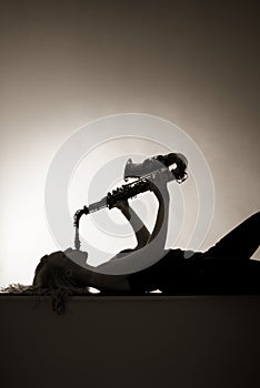 Silhouette of woman playing saxophone, sepia toned