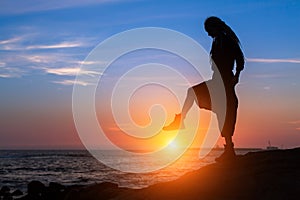 Silhouette woman posing on the sea shore during amazing sunset.