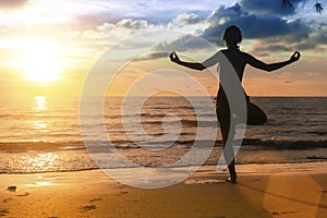 Silhouette of woman practicing yoga during amazing sunset.