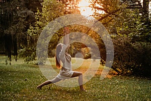 Silhouette woman practicing yoga in the forest at sunset. Meditation workout concept.