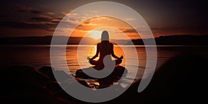 Silhouette of a woman practicing yoga or meditating on the beach at sunrise. Yoga concept