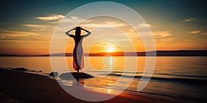 Silhouette of a woman practicing yoga or meditating on the beach at sunrise. Yoga concept