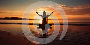 Silhouette of a woman practicing yoga or meditating on the beach at sunrise. Yoga concept