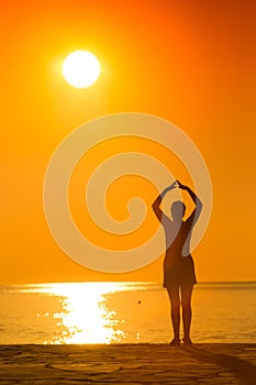 Silhouette of woman practicing yoga on the sunset