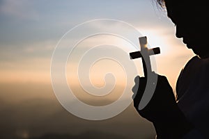 Silhouette of woman  praying with cross  in nature sunrise background,  Crucifix, Symbol of Faith. Christian life crisis prayer to