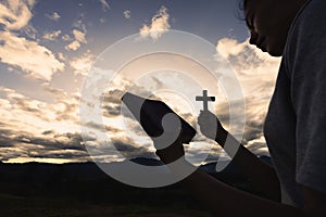 Silhouette of woman praying with cross in nature sunrise background, Crucifix, Symbol of Faith. Christian life crisis prayer to
