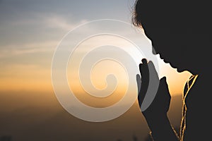 Silhouette of a woman  Praying hands with faith in religion and belief in God On the morning sunrise background.  Namaste or