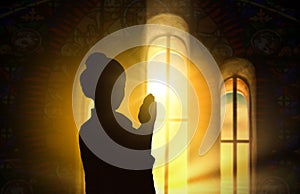 Silhouette of a woman praying inside a church