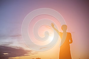 Silhouette of woman praying over beautiful sky background