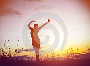 Silhouette of woman praying over beautiful sky background