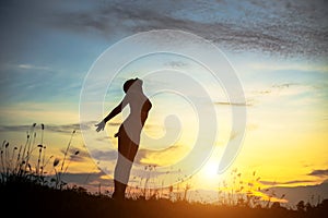 Silhouette of woman praying over beautiful sky background