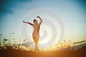 Silhouette of woman praying over beautiful sky background