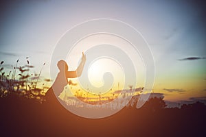 Silhouette of woman praying over beautiful sky background