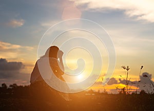 Silhouette of woman praying over beautiful sky background