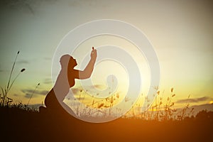 Silhouette of woman praying over beautiful sky background