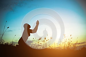 Silhouette of woman praying over beautiful sky background