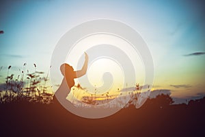 Silhouette of woman praying over beautiful sky background