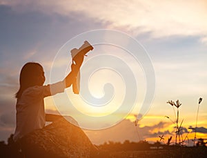 Silhouette of woman praying over beautiful sky background