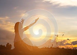 Silhouette of woman praying over beautiful sky background