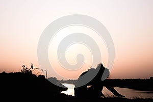 Silhouette of woman praying over beautiful sky background