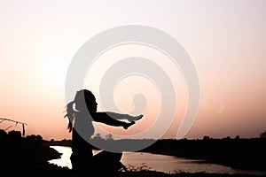 Silhouette of woman praying over beautiful sky background