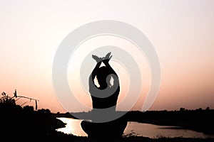 Silhouette of woman praying over beautiful sky background