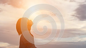 Silhouette of woman praying over beautiful sky background