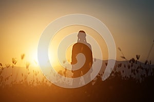 Silhouette of woman praying over beautiful sky