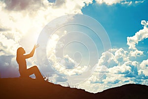 Silhouette of woman praying over beautiful sunrise