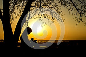 Silhouette of woman praying to God in the nature witth the Bible at sunset, the concept of religion and spirituality