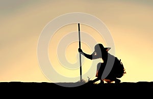 Silhouette of Woman Pulling Weeds from Garden photo