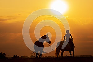 Silhouette of a woman riding a horse and the other is on a rope