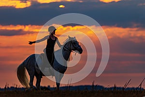 Silhouette of a woman riding a horse at sundown, the sky is beautifully colored