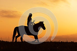 Silhouette of a woman riding a horse after sunset