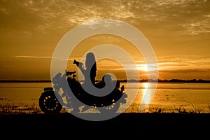 Silhouette woman riding motor bike with sunset. Travel Concept