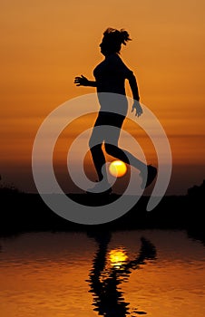 Silhouette woman running against orange sunset