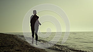 Silhouette woman running beach at sunset. Girl jogging seacoast summer evening.